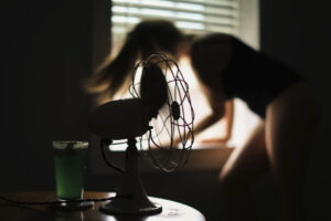 image of woman beside an electric fan